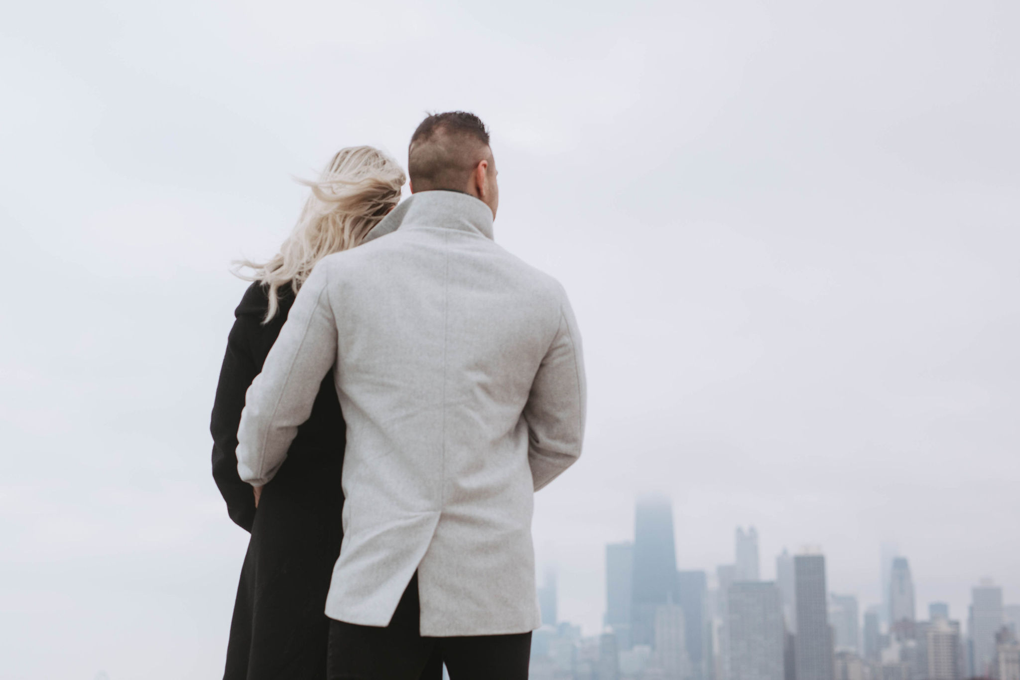 An engaged couple looking out over the city of Chicago during their engagement photo photoshoot