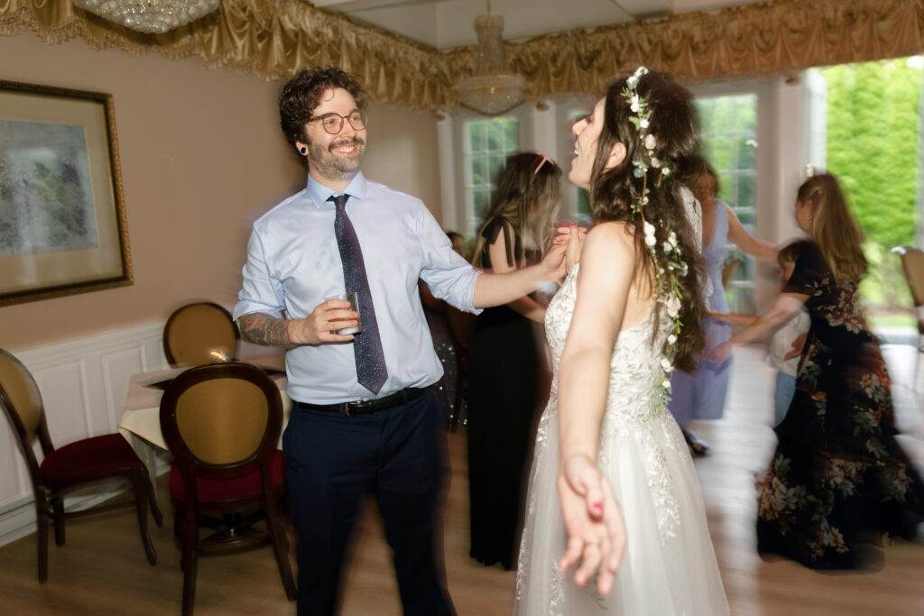 Bride and groom dance together during their Bella Tori wedding reception, laughing and glowing