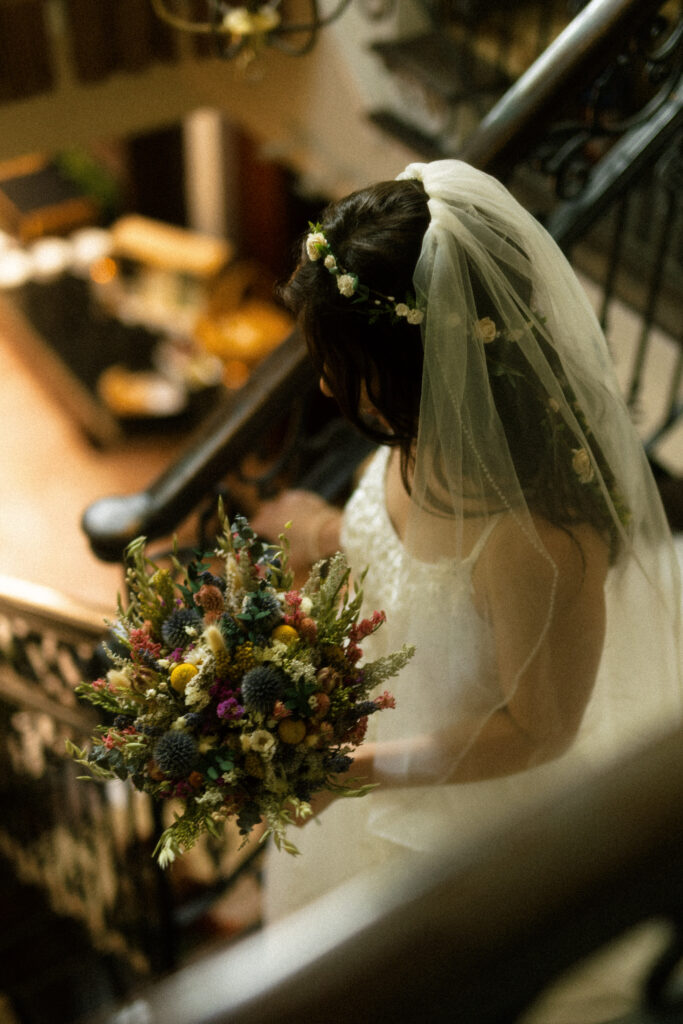 Rachel walks down the vintage staircase inside Bella Tori at the Mansion in her wedding gown