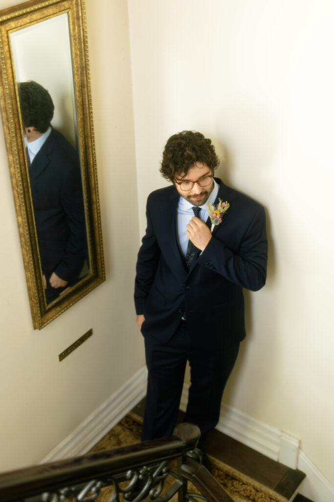 Jake, the groom, standing on the grand staircase inside Bella Tori at the Mansion